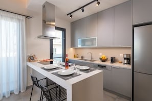 A modern kitchen with a central island, stainless steel appliances, and a large window.