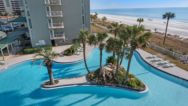 A resort with a swimming pool, palm trees, and a beach view. - Experience luxury in this 3-bedroom oceanfront condo in Panama City Beach. (Panama City Beach)
