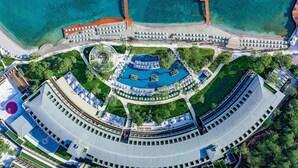 Vue aérienne d’un complexe hôtelier doté d’une piscine centrale, de plusieurs espaces de baignade et d’une plage.
