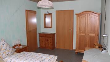 Un dormitorio con cama, armario de madera, mesita de noche, escritorio y silla.