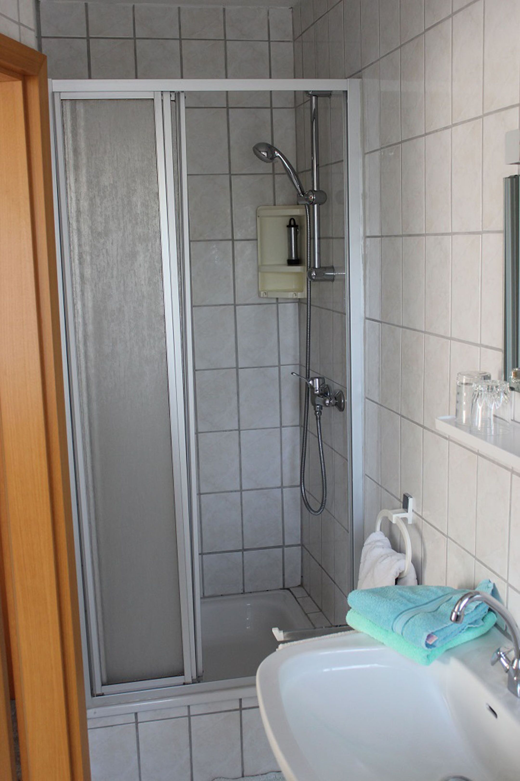Un baño con cabina de ducha, lavamanos y espejo.
