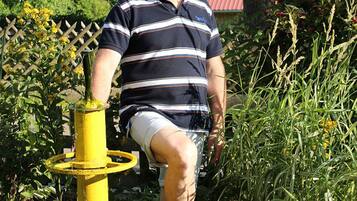 A person standing in a concrete basin with a yellow pump, surrounded by greenery and a fence.