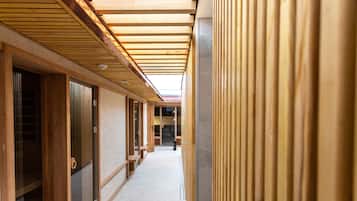 Un pasillo con vigas de madera y puertas correderas, que conduce a una habitación con suelo de baldosas.