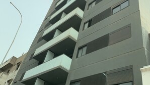 En byggnad med flera våningar, balkonger, stora fönster och en modern arkitektonisk design.