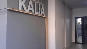 En hall med en skylt på väggen där det står ”KALIA”, en person som bär en keps och en dörr som leder till ett annat rum.