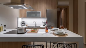 Una cucina moderna con mobili in legno, un frigorifero in acciaio inox, un forno a microonde e un'isola centrale con lavello e angolo ristoro.