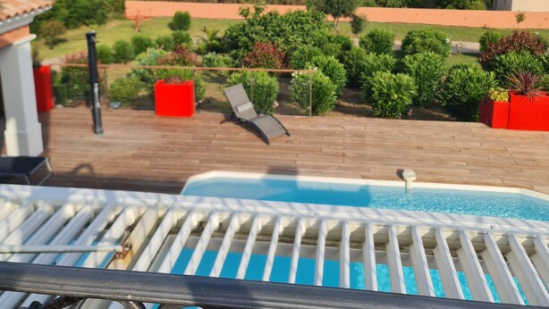Zona de piscina con vista al mar y vegetación circundante.