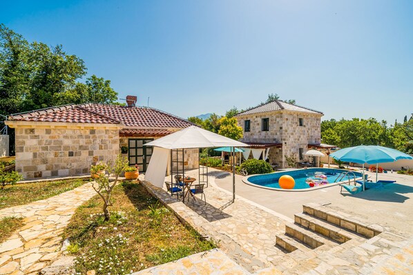 A stone house with a swimming pool, outdoor seating, and a garden.