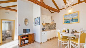 A kitchen with white cabinets, a dining table with yellow chairs, and a painting on the wall. - Dubrovnik Chalets - 2 Charming Stone Houses (Konavle)