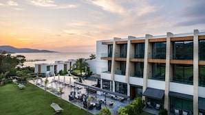 A modern hotel with a pool area, outdoor seating, and a view of the sea at sunset. - The Norm Collection Door'a Bodrum (Bodrum)