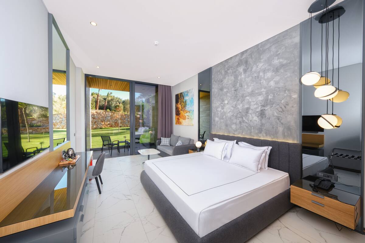 Quarto moderno com uma cama grande, uma escrivaninha e vista para um jardim.
