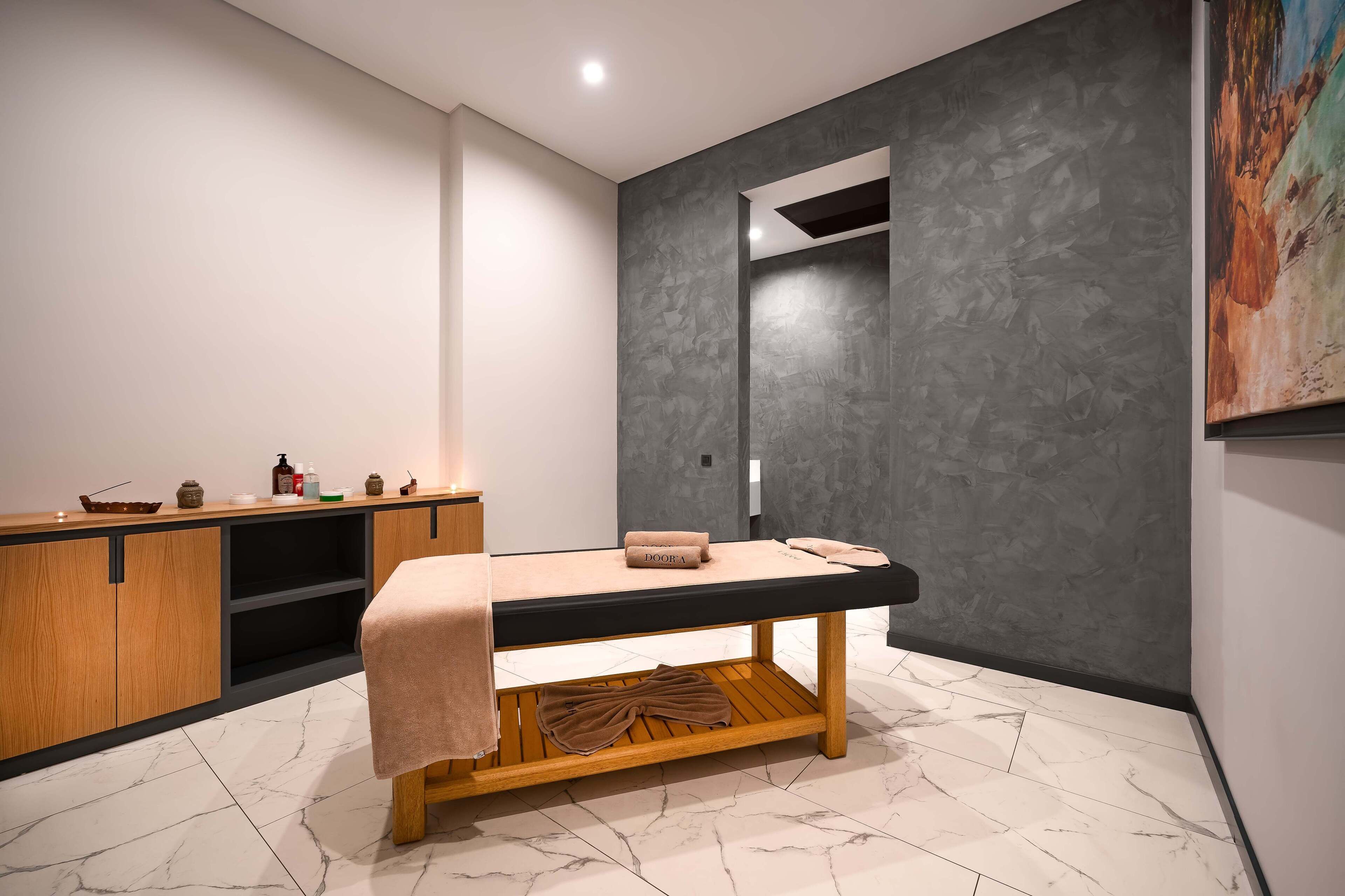 Un spa moderno con una camilla de masaje, armarios de madera y un espejo grande.