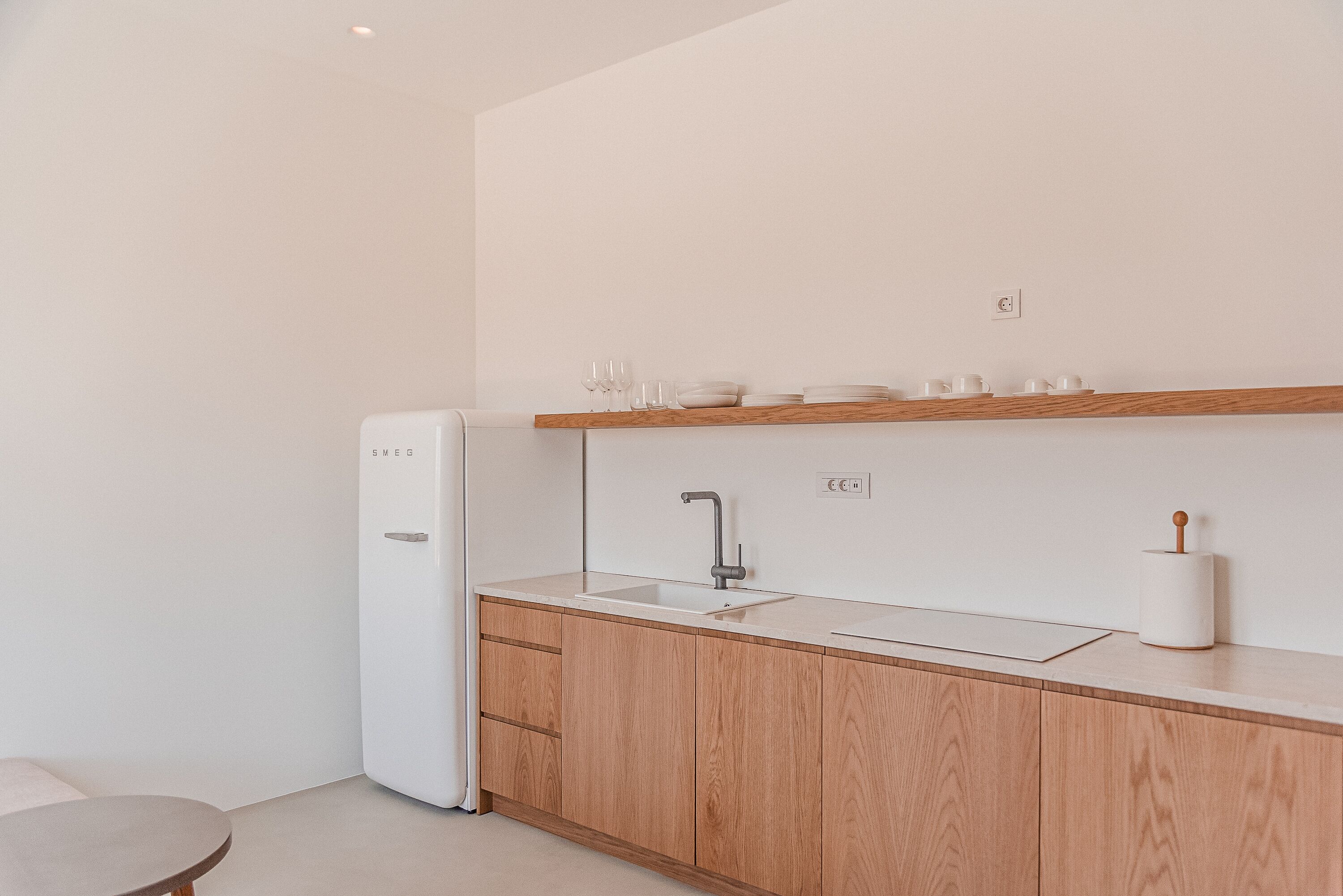 A modern kitchen with wooden cabinets, a white countertop, a built-in sink, and a white refrigerator.