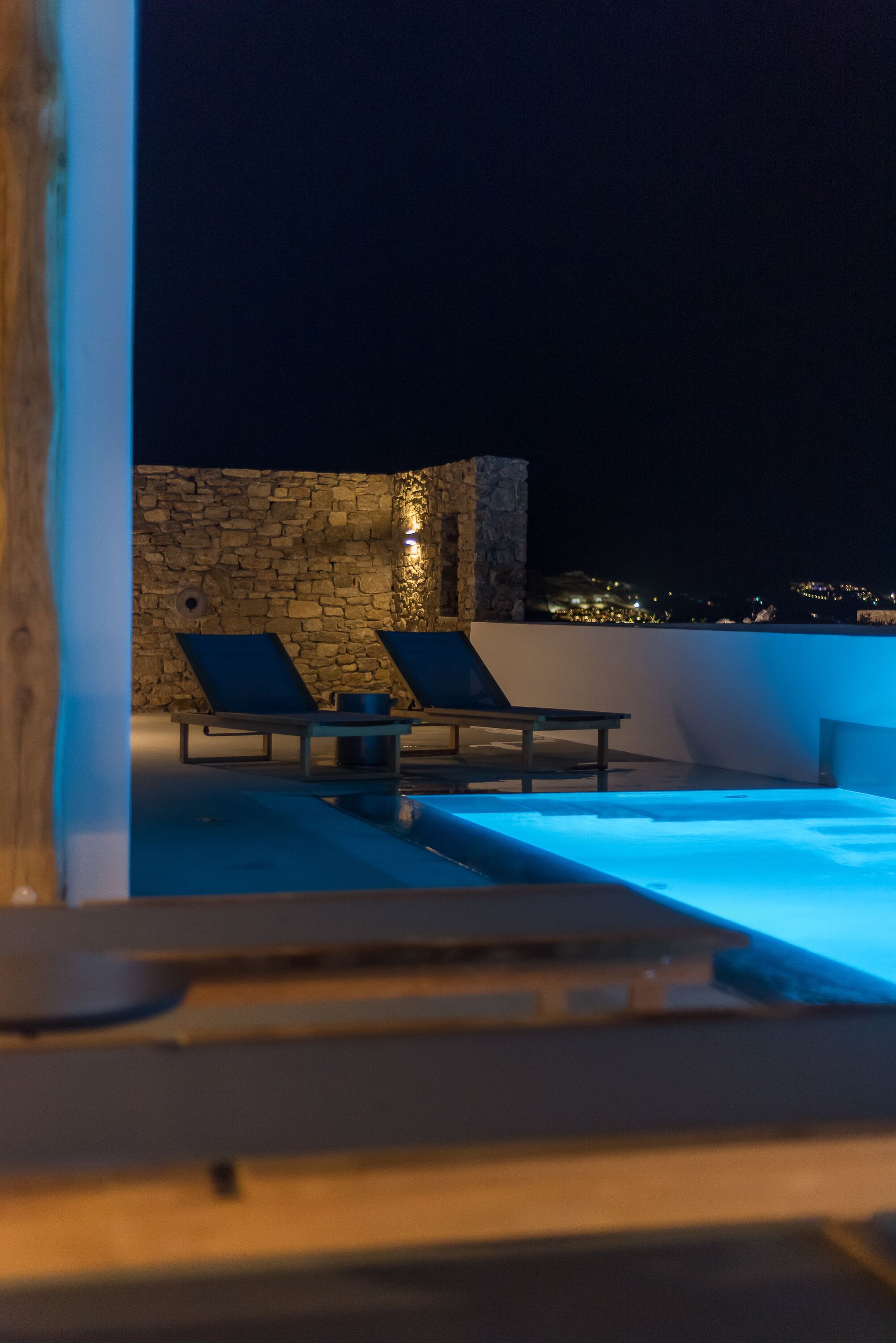 A rooftop pool area with lounge chairs and a stone wall.