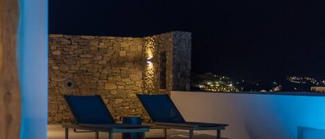 A rooftop pool area with lounge chairs and a stone wall.