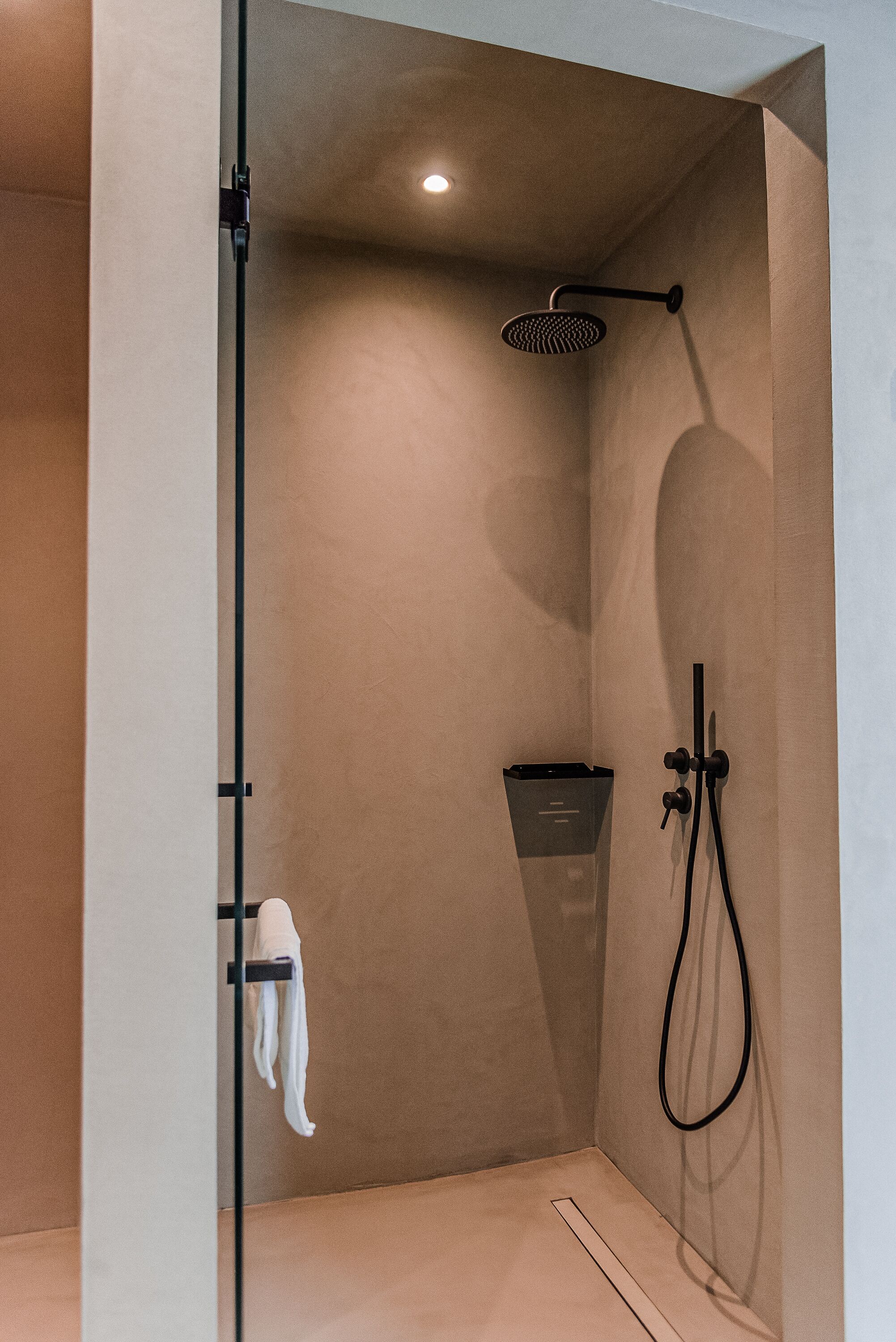 Une douche moderne équipée d’un pommeau de douche à main, d’un porte-serviettes et d’un distributeur de serviettes fixé au mur.