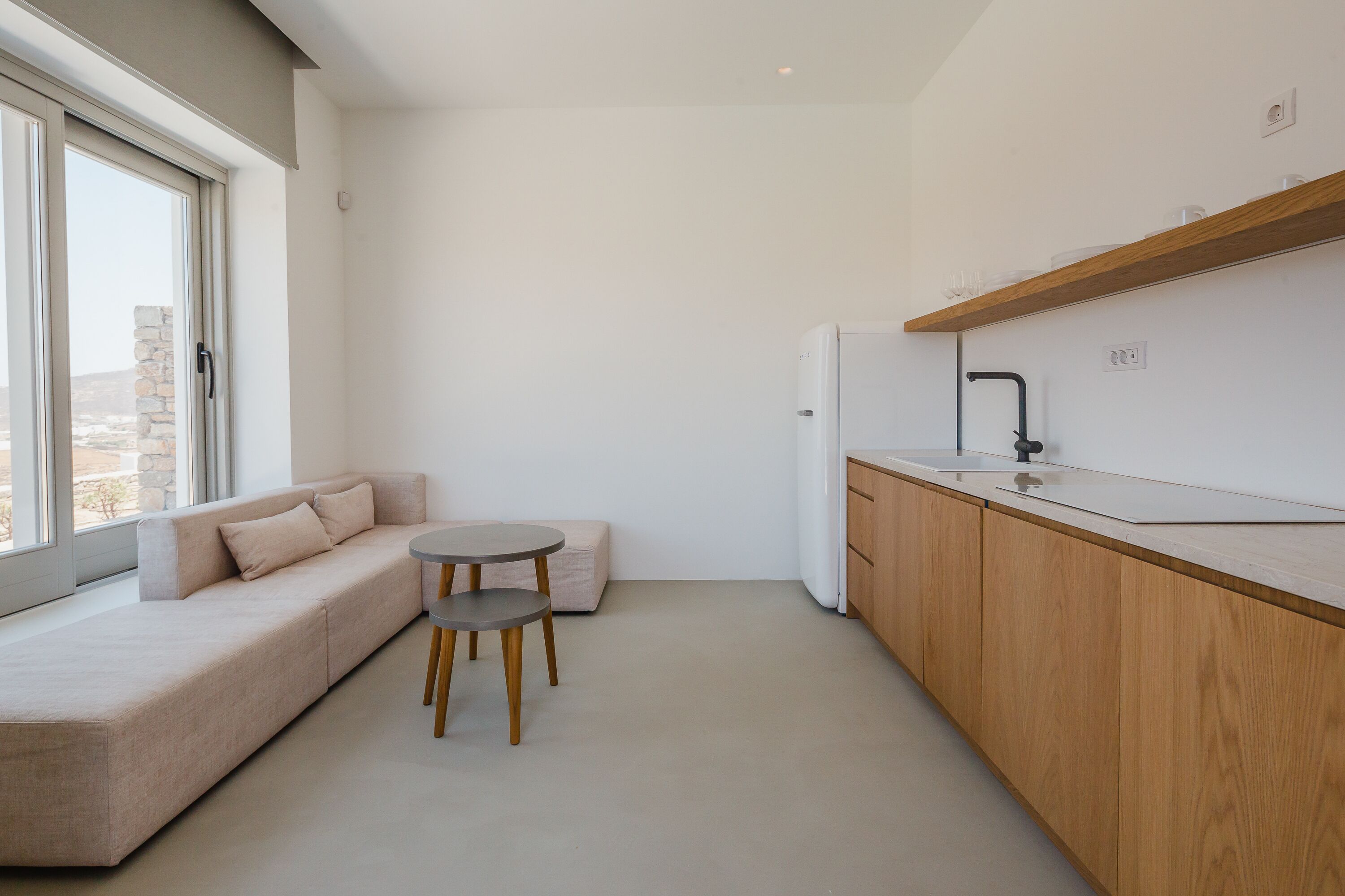 A modern kitchen with wooden cabinets, a built-in oven, and a window overlooking a cityscape.