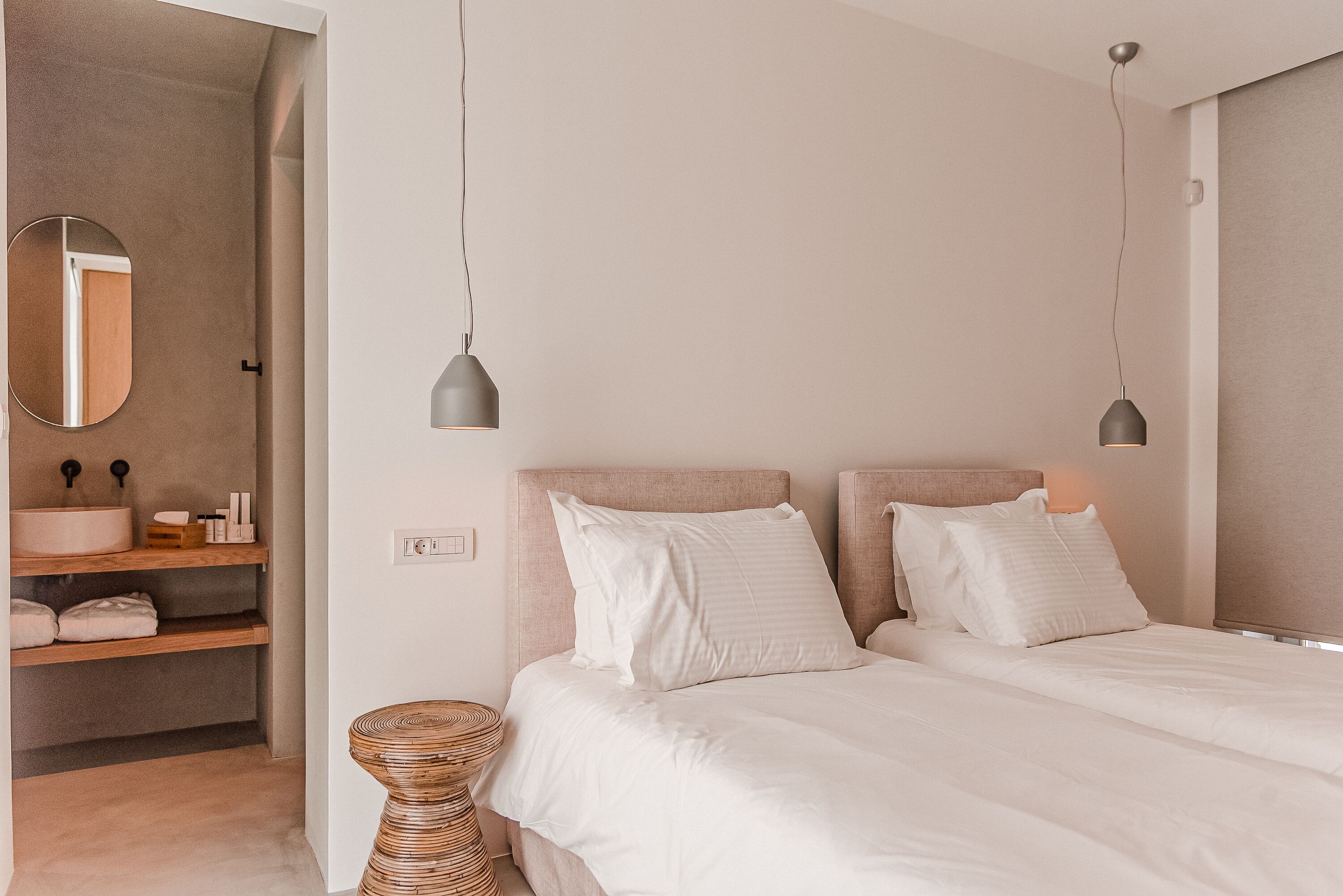 Une chambre à coucher avec un lit, des tables de chevet, un miroir rond et un luminaire suspendu.