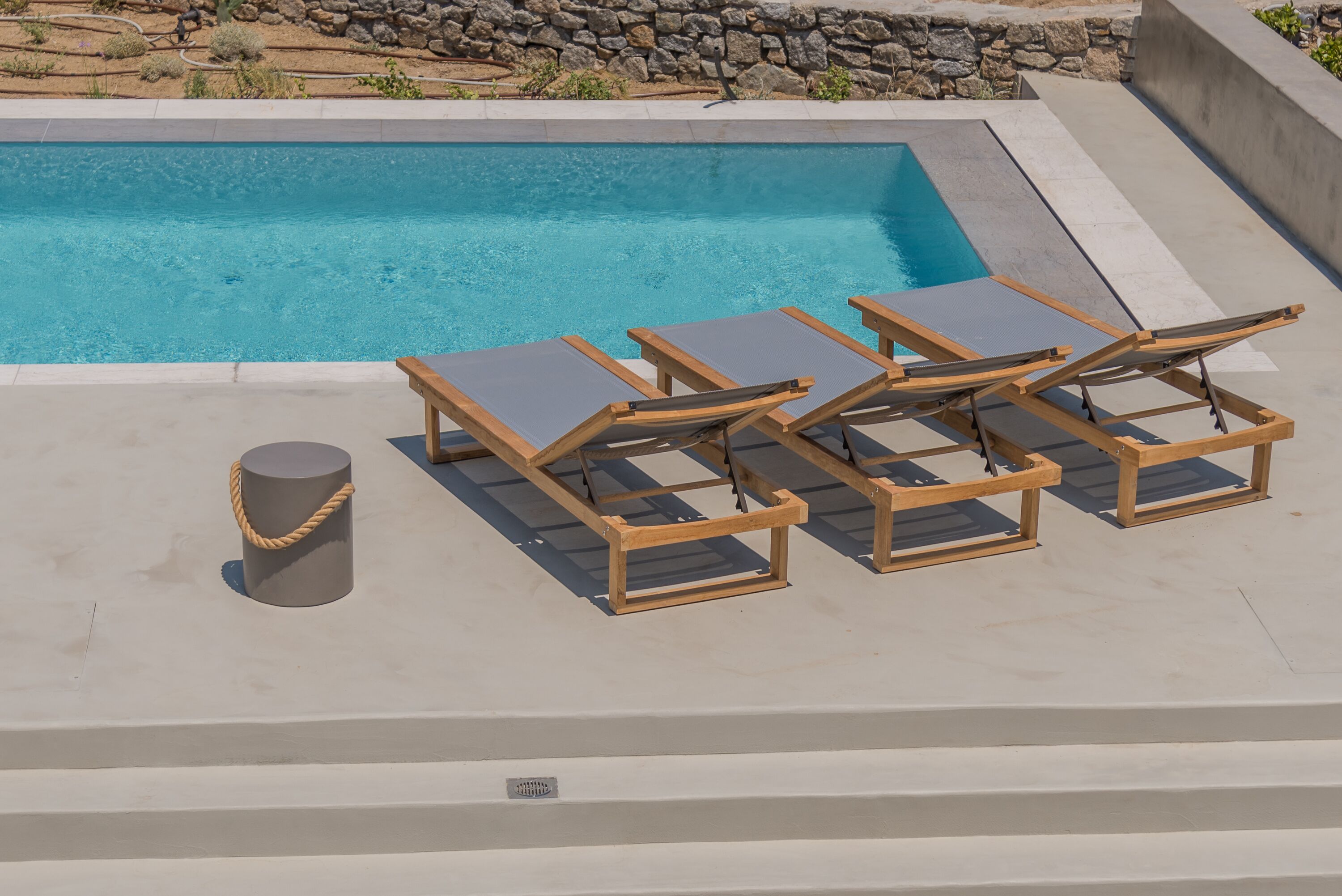 A pool area with lounge chairs and a cylindrical object.