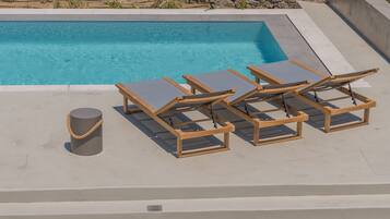A pool area with lounge chairs and a cylindrical object.