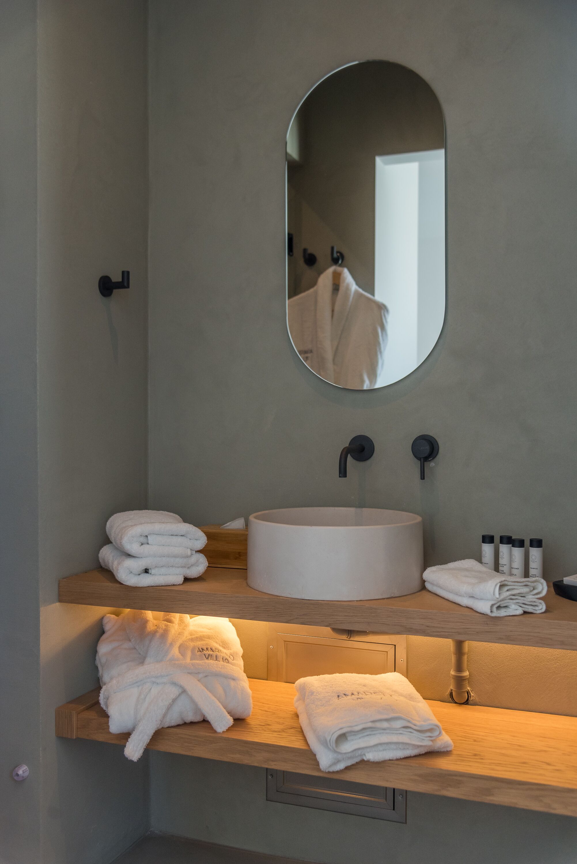 A bathroom with a round sink, a mirror, and towels on the counter.