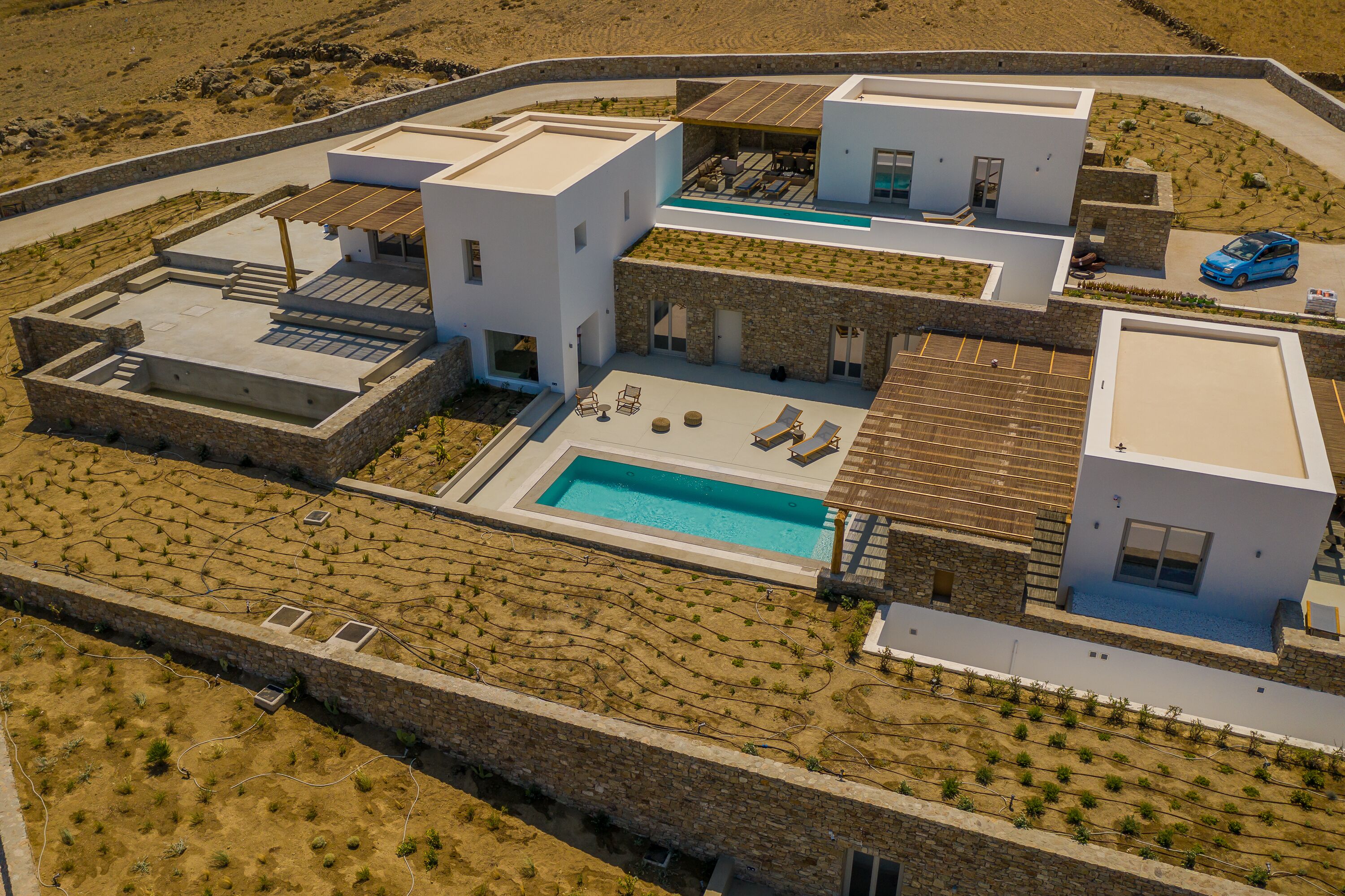 A modern villa with a swimming pool, outdoor seating, and a vineyard.