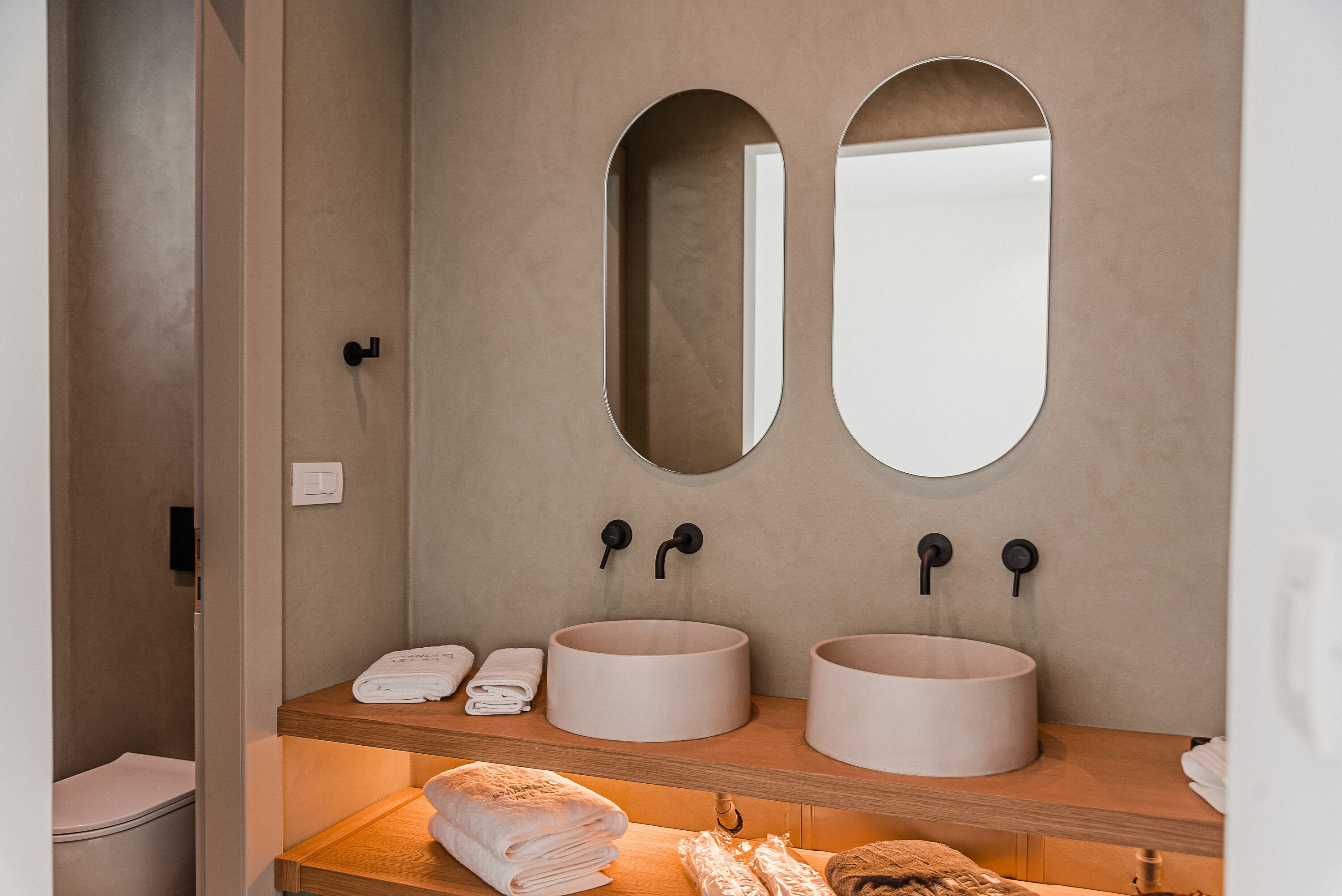 Un baño con dos lavamanos redondos, un espejo y un tocador de madera.