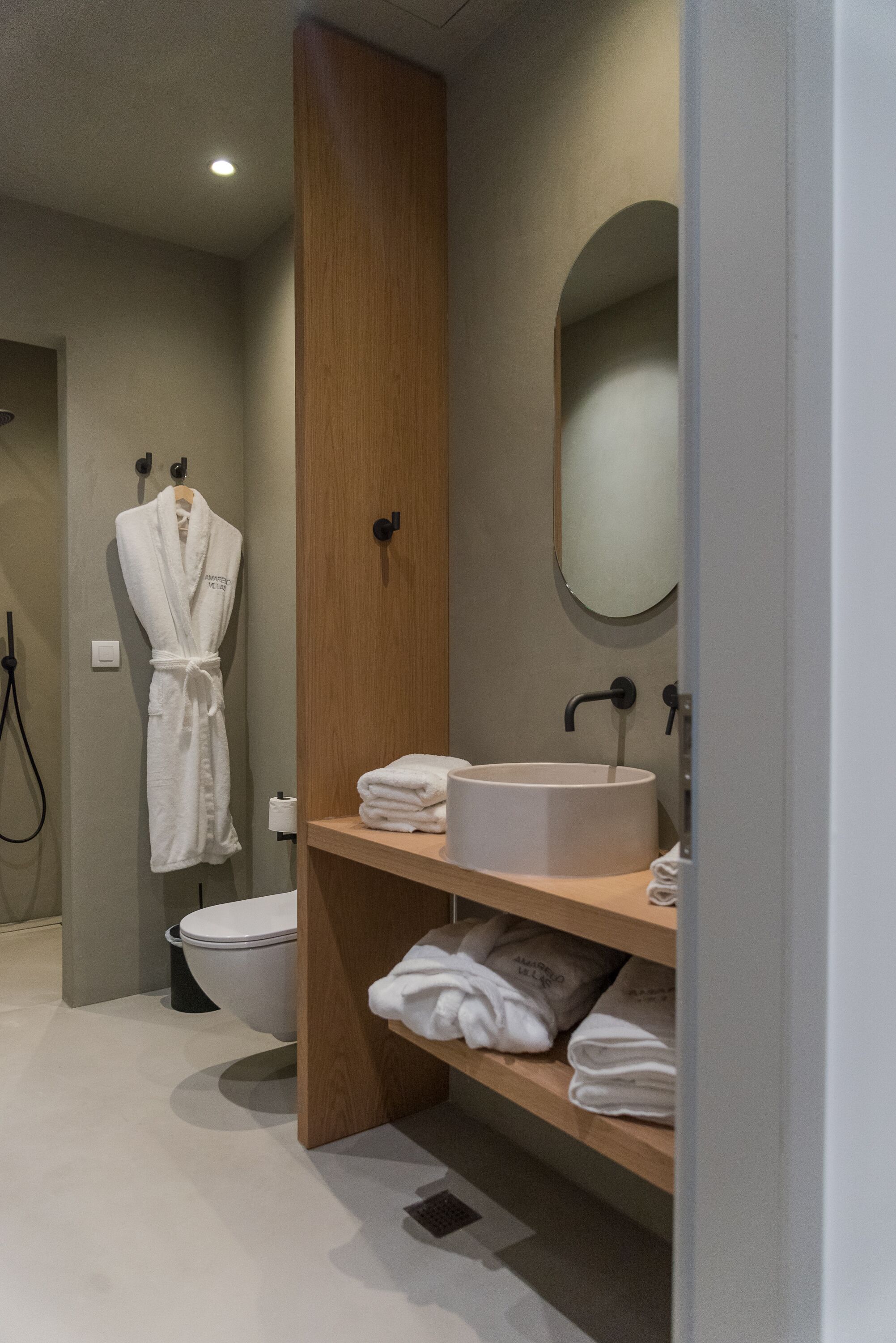 A modern bathroom with a wooden vanity, a white sink, and a toilet.