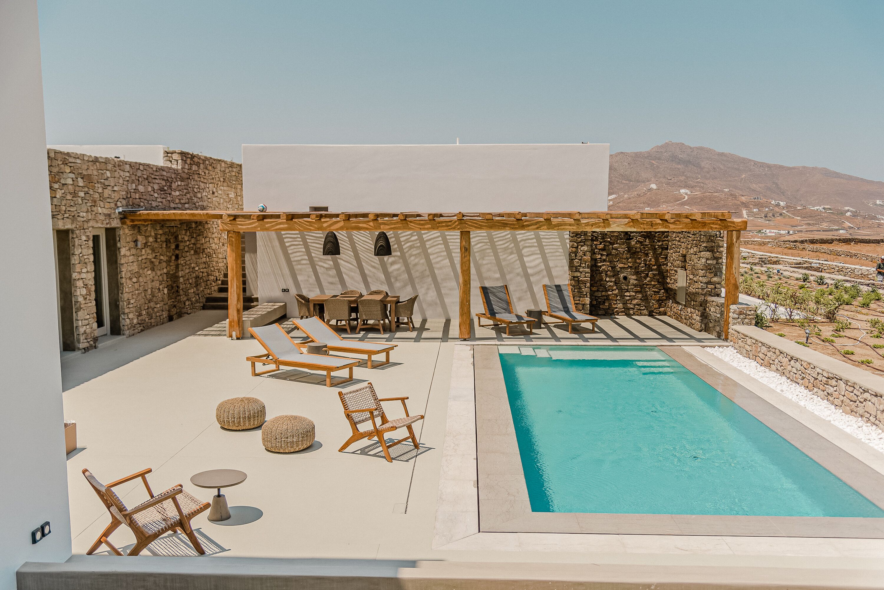 Un espace piscine aménagé sur le toit, avec des chaises longues, une pergola et une vue sur le paysage environnant.