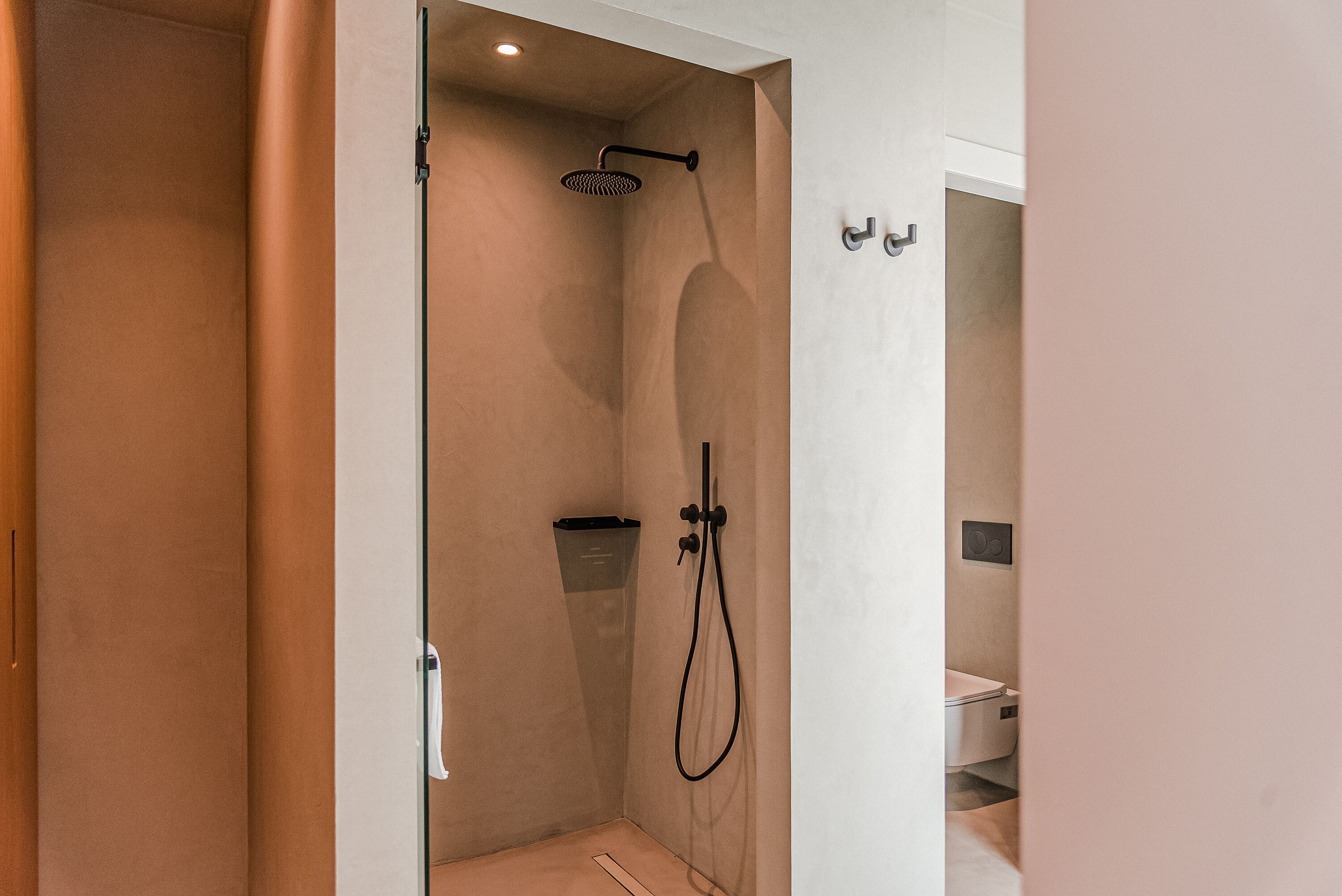 A modern shower with a handheld showerhead and a wall-mounted faucet.