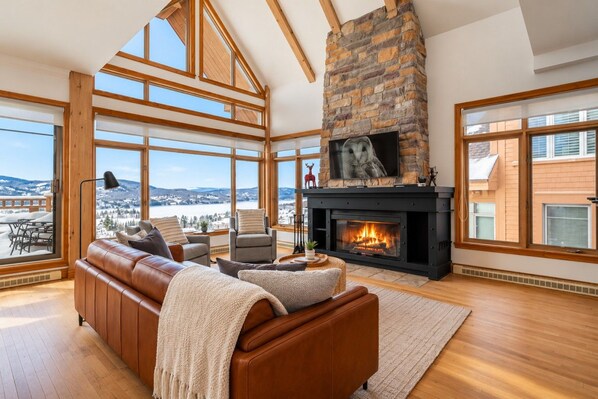 Amplia sala de estar con chimenea, ventanas grandes y vista a un paisaje nevado.