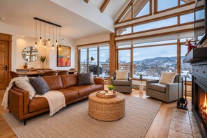 A spacious living room with a leather sofa, a round wicker coffee table, and a fireplace.