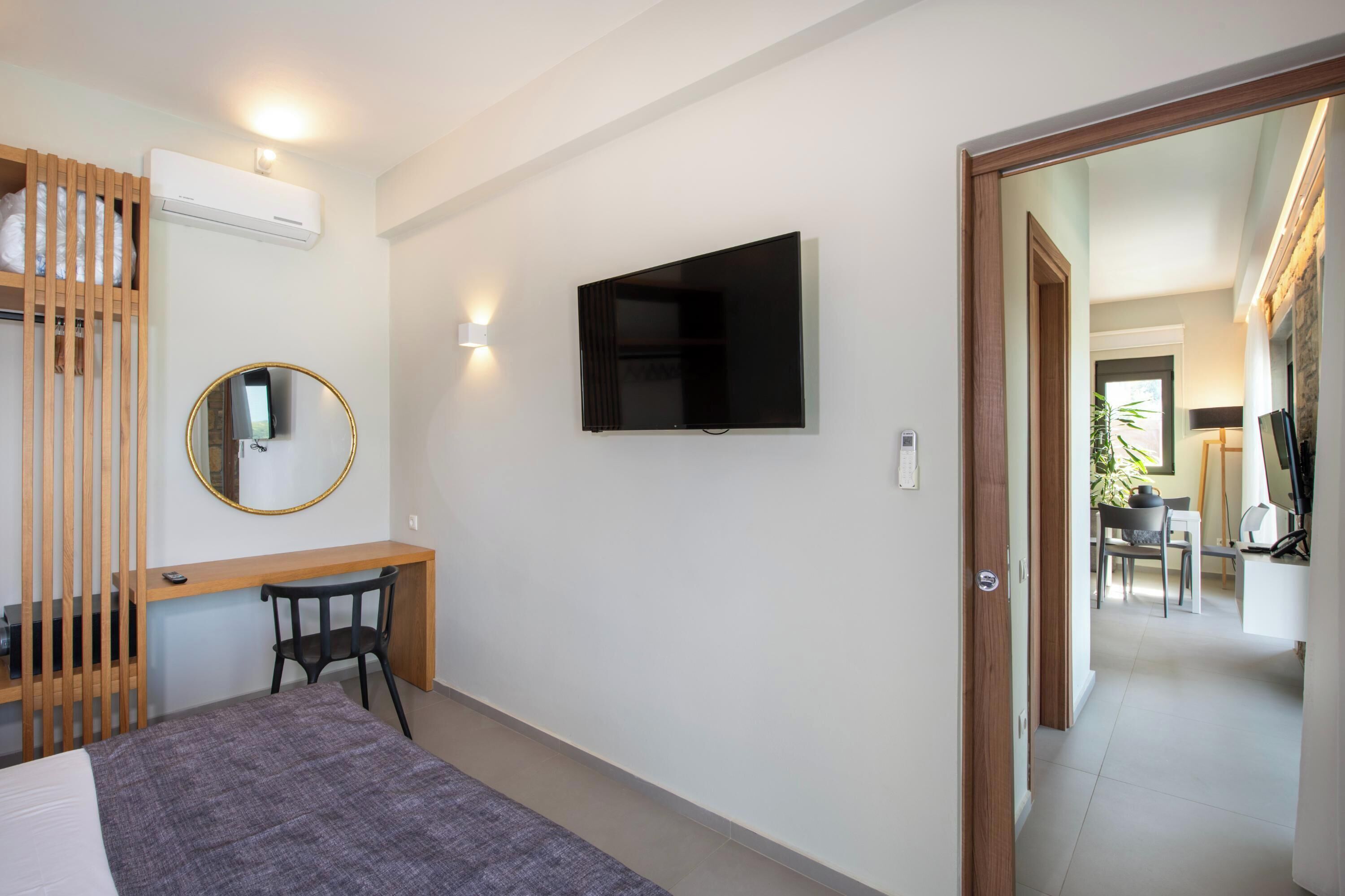 Une chambre à coucher comprenant un lit, un bureau, une chaise, un téléviseur fixé au mur et un appareil de climatisation.