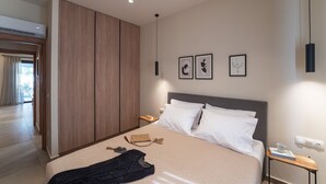 A modern hotel room with a bed, a nightstand, a desk, and a wardrobe.