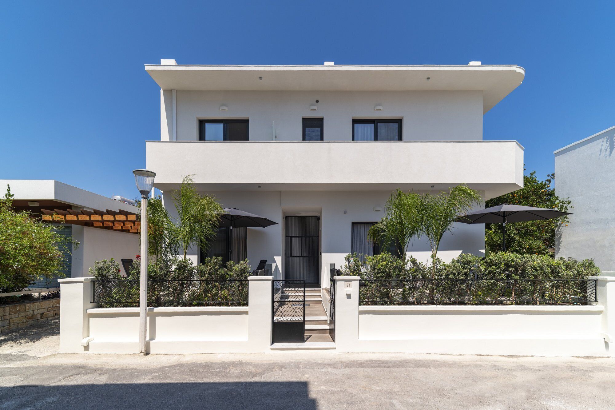 Une maison moderne à deux étages, dotée d’un toit plat, d’une entrée principale et d’un petit porche.