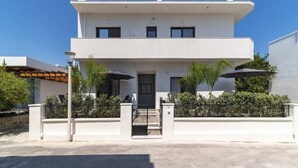 A modern two-story house with a flat roof, a front entrance, and a small porch area.