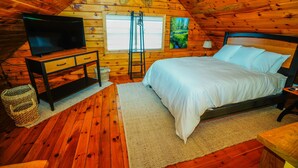 Een knus slaapkamer met houten lambrisering, een bed, een televisie en een raam met blinds.