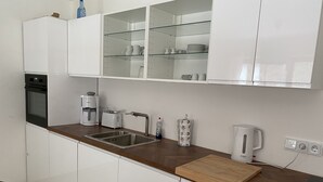 Een moderne keuken met witte kastjes, een roestvrijstalen spoelbak, een Bosch koffiezetapparaat en een houten snijplank.