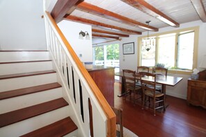 A wooden staircase leading to a dining area with a table and chairs. - Private Cottage Compound On Ryders Pond with Pristine Yard (2215) (Truro)