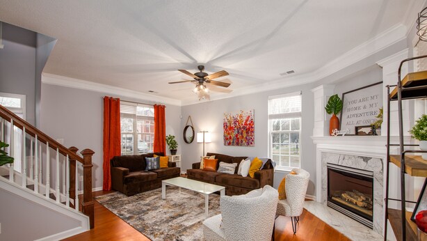 A living room with hardwood floors, a ceiling fan, a fireplace, and a staircase. - Carowinds 2Miles, Fully Fenced Yard, 2,000sq ft House, 5Min Highway (Charlotte)