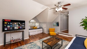 A modern living room with a flat-screen TV, a ceiling fan, a sofa, a yellow chair, and a wooden coffee table. - Carowinds 2Miles, Fully Fenced Yard, 2,000sq ft House, 5Min Highway (Charlotte)