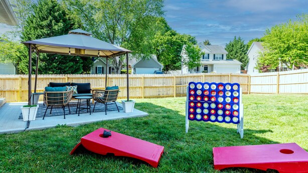 A backyard with a covered patio, outdoor furniture, and a game board. - Carowinds 2Miles, Fully Fenced Yard, 2,000sq ft House, 5Min Highway (Charlotte)