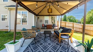 A covered patio area with outdoor furniture, including a sofa, chairs, and a table. - Carowinds 2Miles, Fully Fenced Yard, 2,000sq ft House, 5Min Highway (Charlotte)