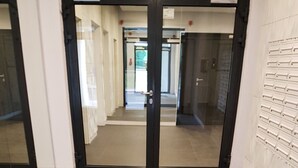 Un pasillo con una puerta de cristal que da a un espacio interior, con la inscripción 