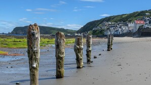 A beach with wooden posts and a coastal town in the background. - Ellie-Jo Cottage (Gardenstown)