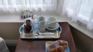 A breakfast tray with cups, plates, and pastries on a wooden table by a window with sheer curtains. - Bow Street Runner (Hove)