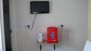 A room with a television mounted on the wall, a red iceQ coffee machine, and a white coffee maker on a small wooden shelf. - Bow Street Runner (Hove)