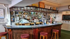 A bar area with a wooden counter, stools, and a variety of bottles and glasses. - Bow Street Runner (Hove)