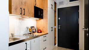 A modern kitchen with white cabinets, a black microwave, and a black door. - Easy Rent Nieruchomości - SMART 316 (Lublin)