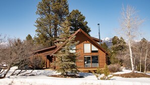 A log cabin with a large window, surrounded by snow and trees. - 3BR Pet Friendly | Mountain Views, Dark Skies, Walk to Trails, Exceptional Coffee (Pagosa Springs)